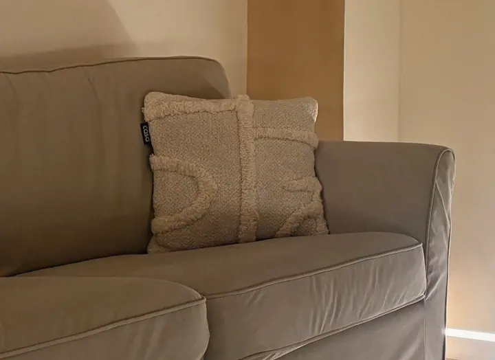 A close crop of the bouclé cushion in the lounge, its looped texture in raking light.